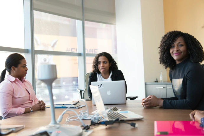photographie de trois femmes assises à côté d'une table à l'intérieur d'une pièce pendant la journée